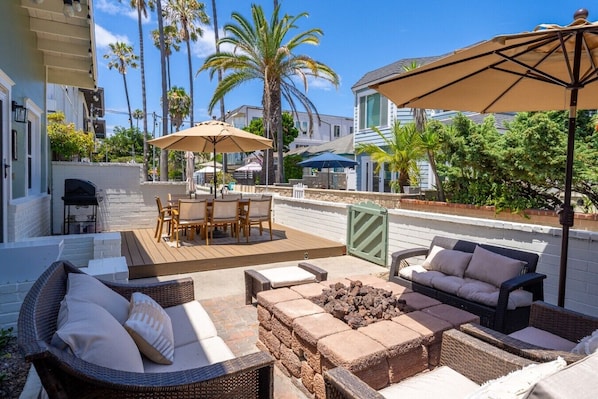 Un espace patio amĂ©nagĂ© avec du mobilier dâextĂ©rieur, un barbecue et des parasols.