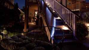 Une maison à plusieurs niveaux avec un escalier, un espace extérieur aménagé pour s’asseoir et une entrée bien éclairée.