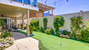 Un espace extérieur bien entretenu, comprenant une terrasse, une petite pelouse et diverses plantes.