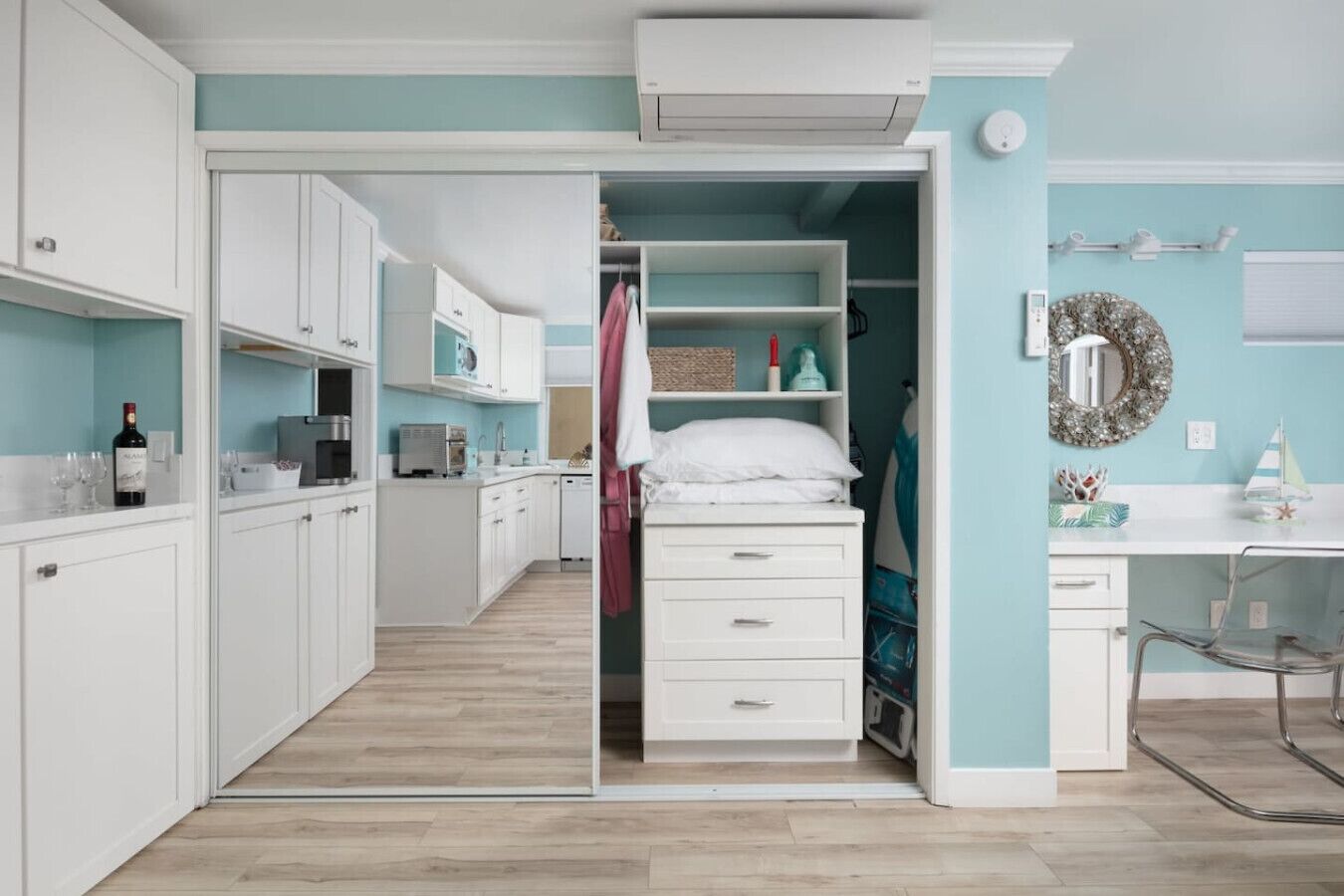 A modern kitchen with white cabinets, a microwave, and a wine bottle.