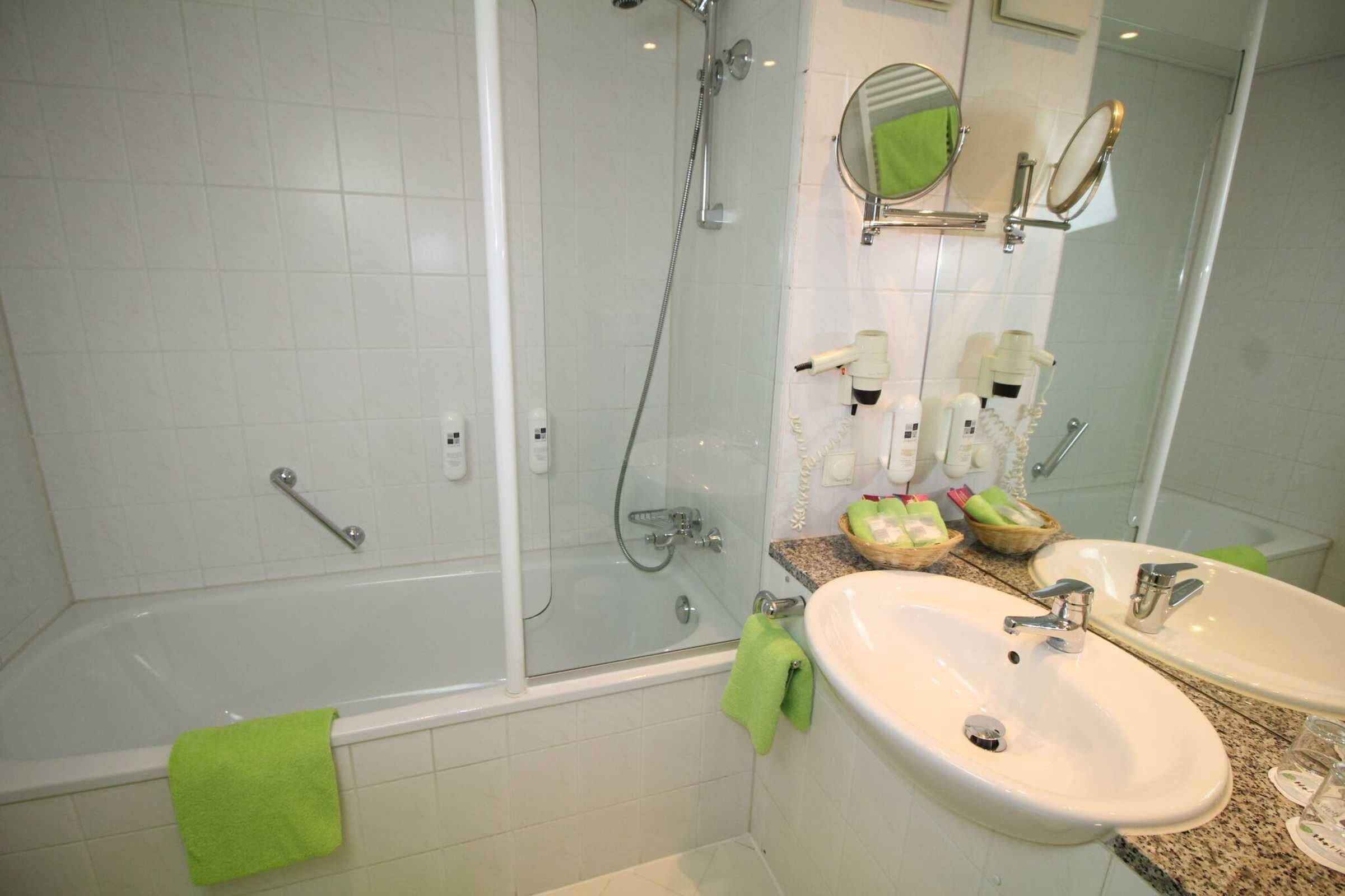 Een moderne badkamer met een douche met glazen wand, twee wastafels en een grote spiegel.