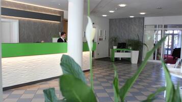 A reception area with a green counter, a white pillar, and a checkered floor.