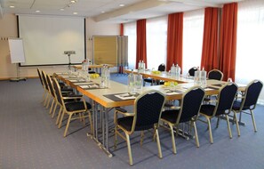 Ett konferensrum med ett långt bord, stolar, en projektorduk och en whiteboard.