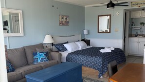 Ein Schlafzimmer mit Bett, Sofa, Couchtisch, Esstisch und Deckenventilator.