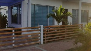 A modern house with a covered porch, large windows, and a wooden fence. - Tierra Linda Girardot (Girardot)