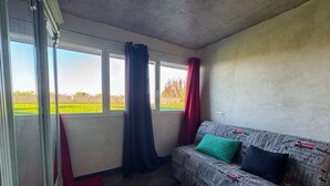 A room with a sofa, a window with curtains, and a view of a field. - Spacious villa with terrace and garden, pets and parking allowed (Lugrin)