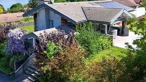 A modern house with a sloped roof, solar panels, and a view of mountains and a lake. - Spacious villa with terrace and garden, pets and parking allowed (Lugrin)