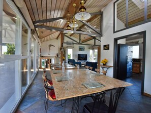 A spacious dining area with a large table, chairs, and a ceiling with exposed beams and hanging lights.