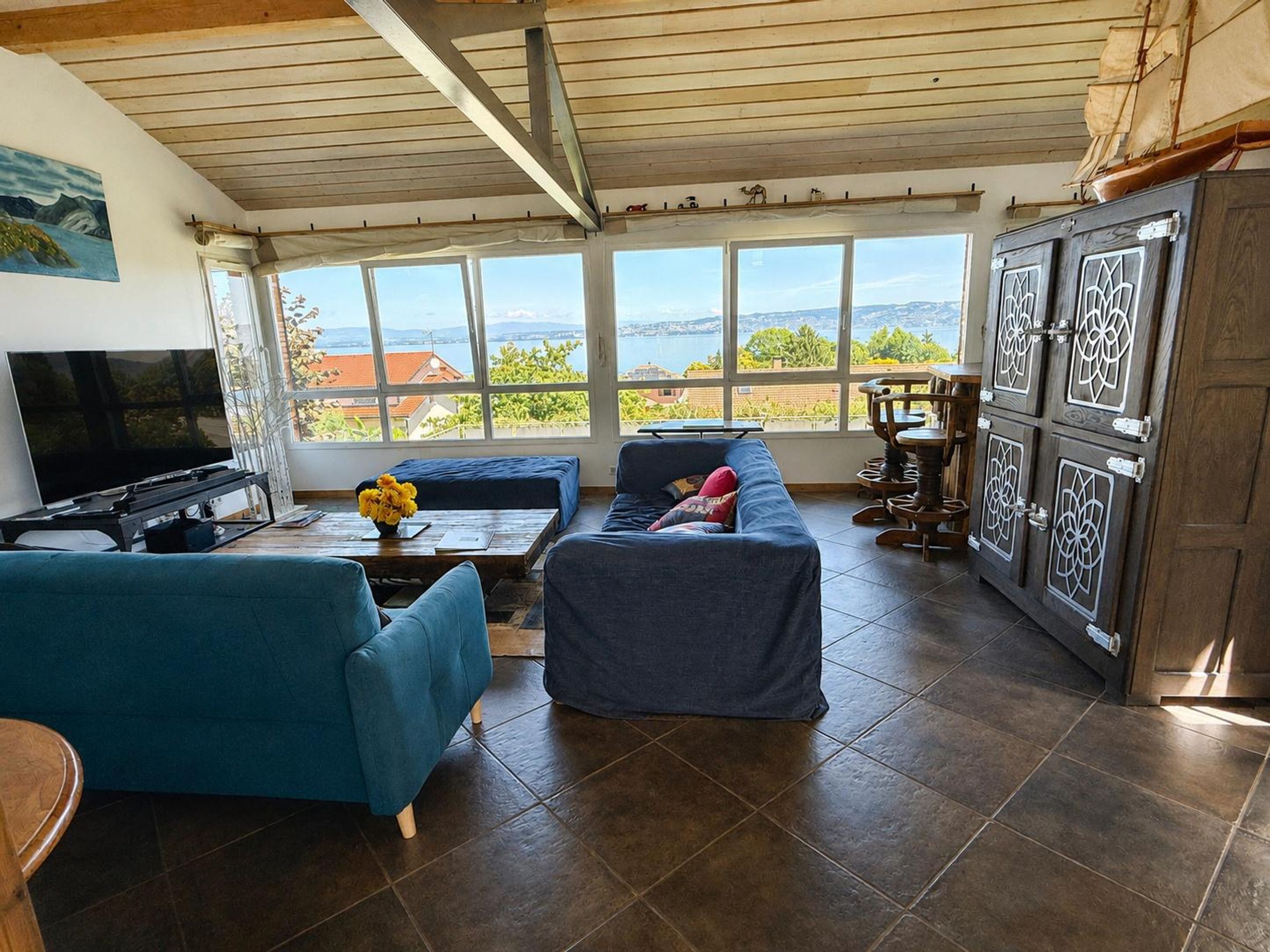 Un salon avec une télévision, un canapé et une vue sur la mer.