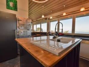 A modern kitchen with a wooden countertop, stainless steel appliances, and large windows offering a view of the outdoors. - Spacious villa with terrace and garden, pets and parking allowed (Lugrin)