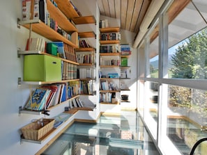 Een moderne bibliotheek met boekenkasten en een glazen vloer, met uitzicht op het omliggende landschap.