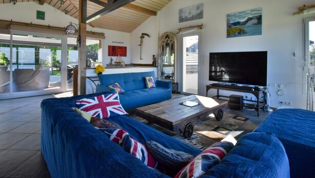A spacious living room with a blue sofa, a coffee table, and a television. - Spacious villa with terrace and garden, pets and parking allowed (Lugrin)