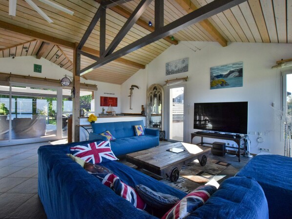A spacious living room with a blue sofa, a coffee table, and a television. - Spacious villa with terrace and garden, pets and parking allowed (Lugrin)