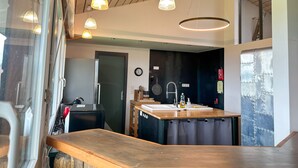 A modern kitchen with a wooden countertop, pendant lights, and a visible clock on the wall. - Spacious villa with terrace and garden, pets and parking allowed (Lugrin)