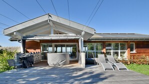 Una casa moderna con un porche cubierto, mobiliario exterior y vistas al paisaje.
