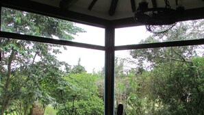A room with two chairs facing a large window overlooking a garden.