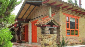 A rustic house with a stone facade, red doors, and a tiled roof.