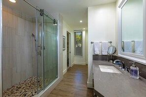 A modern bathroom with a glass-enclosed shower, a vanity with a sink and mirror, and a walk-in shower.