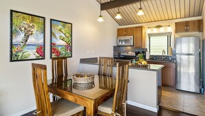 Una cocina moderna con armarios de madera, electrodomésticos de acero inoxidable y un comedor con mesa de vidrio y sillas de madera.