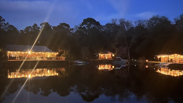 A lakeside hotel with illuminated buildings reflecting on the water, surrounded by trees. - Lake Retreat of Steinhatchee- bring your RV to the place for fun and memories!! (Steinhatchee)