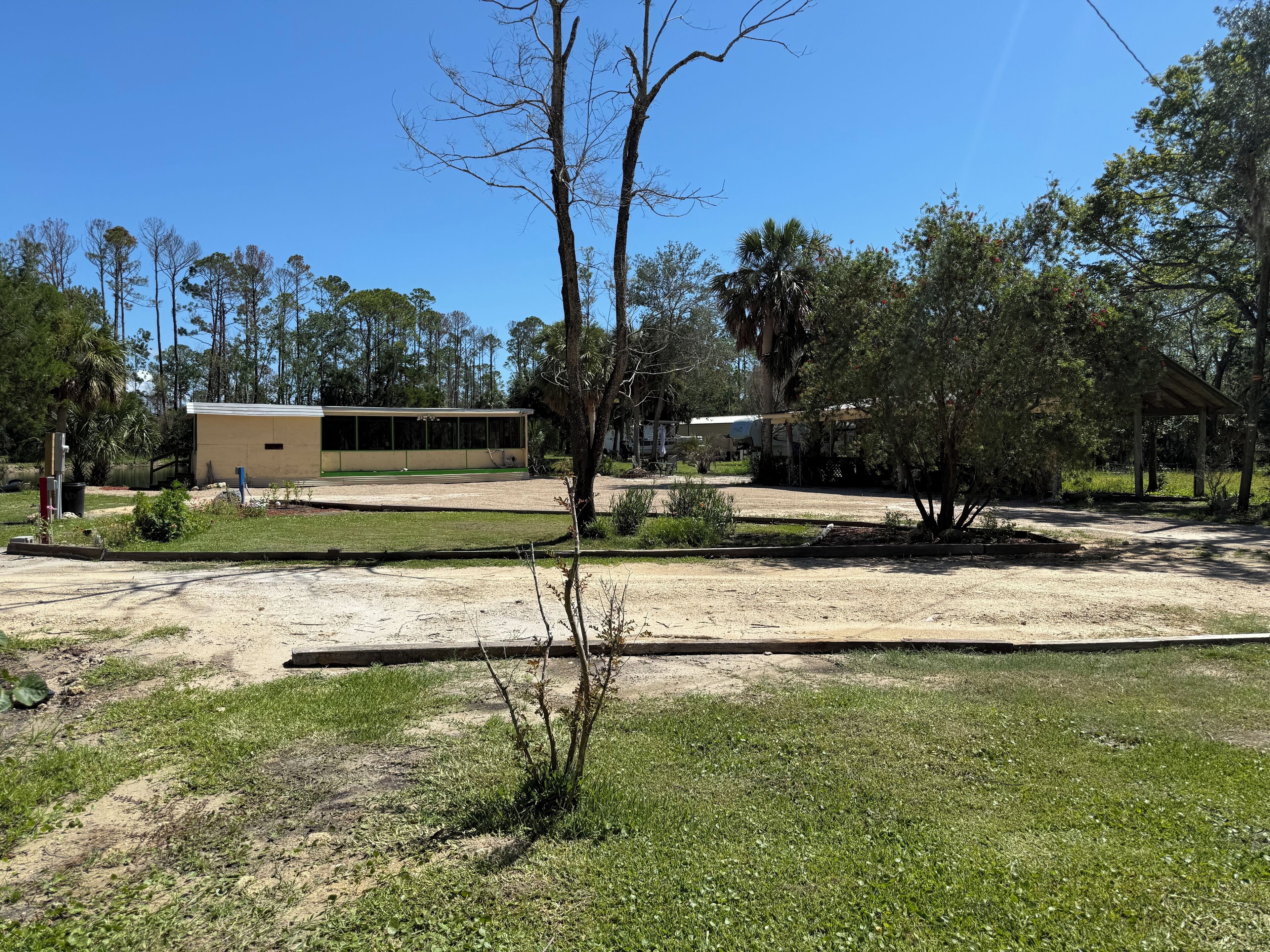 A building with a flat roof and large windows, surrounded by trees and a grassy area.