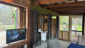 A wooden deck with a television, a grill, and a patio table. - Lake Retreat of Steinhatchee- bring your RV to the place for fun and memories!! (Steinhatchee)