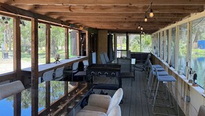 A covered outdoor seating area with wooden beams, a pool table, and a bar area with stools. - Lake Retreat of Steinhatchee- bring your RV to the place for fun and memories!! (Steinhatchee)