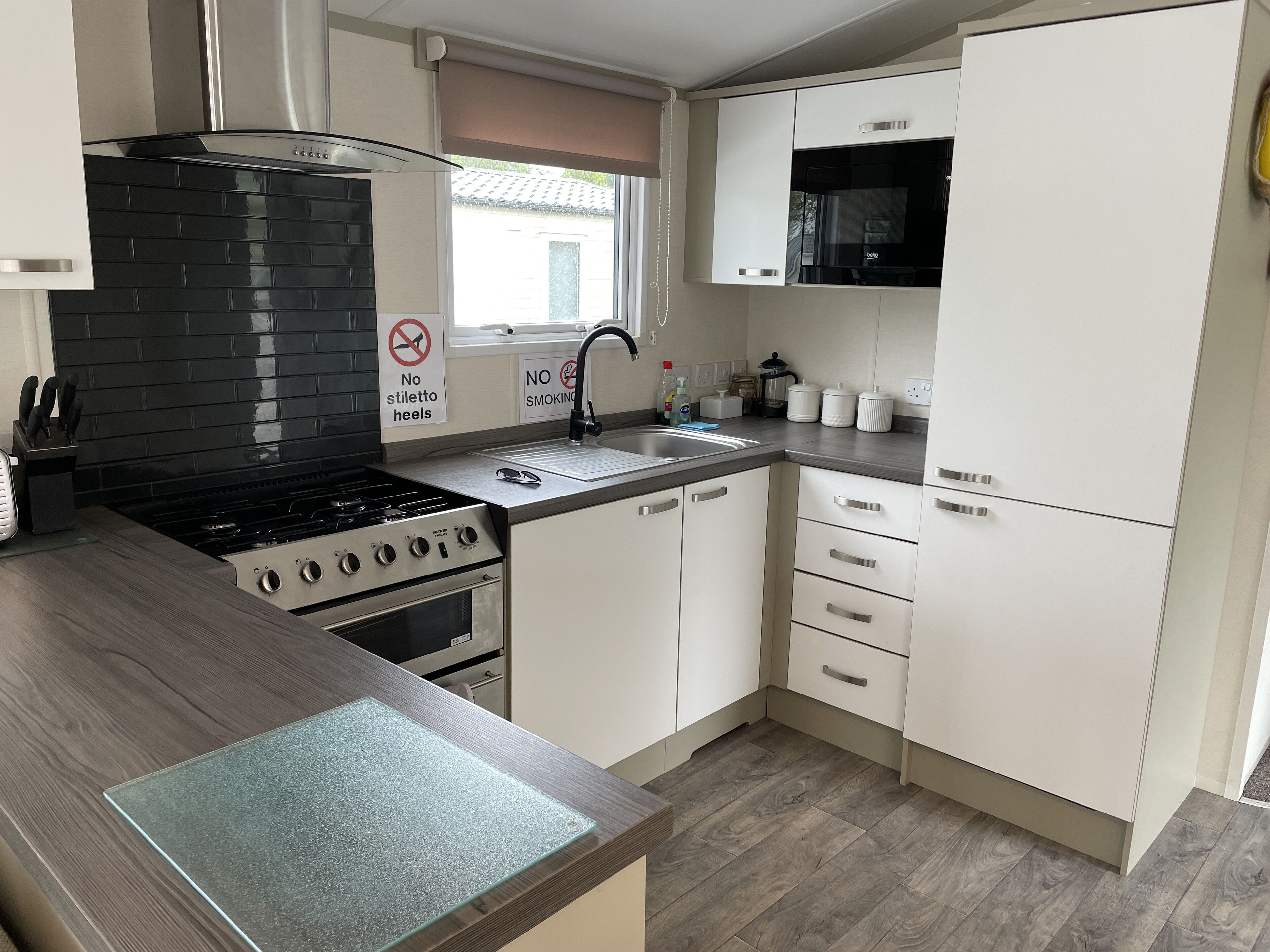 A modern kitchen with a gas stove, oven, white cabinets, and a microwave.