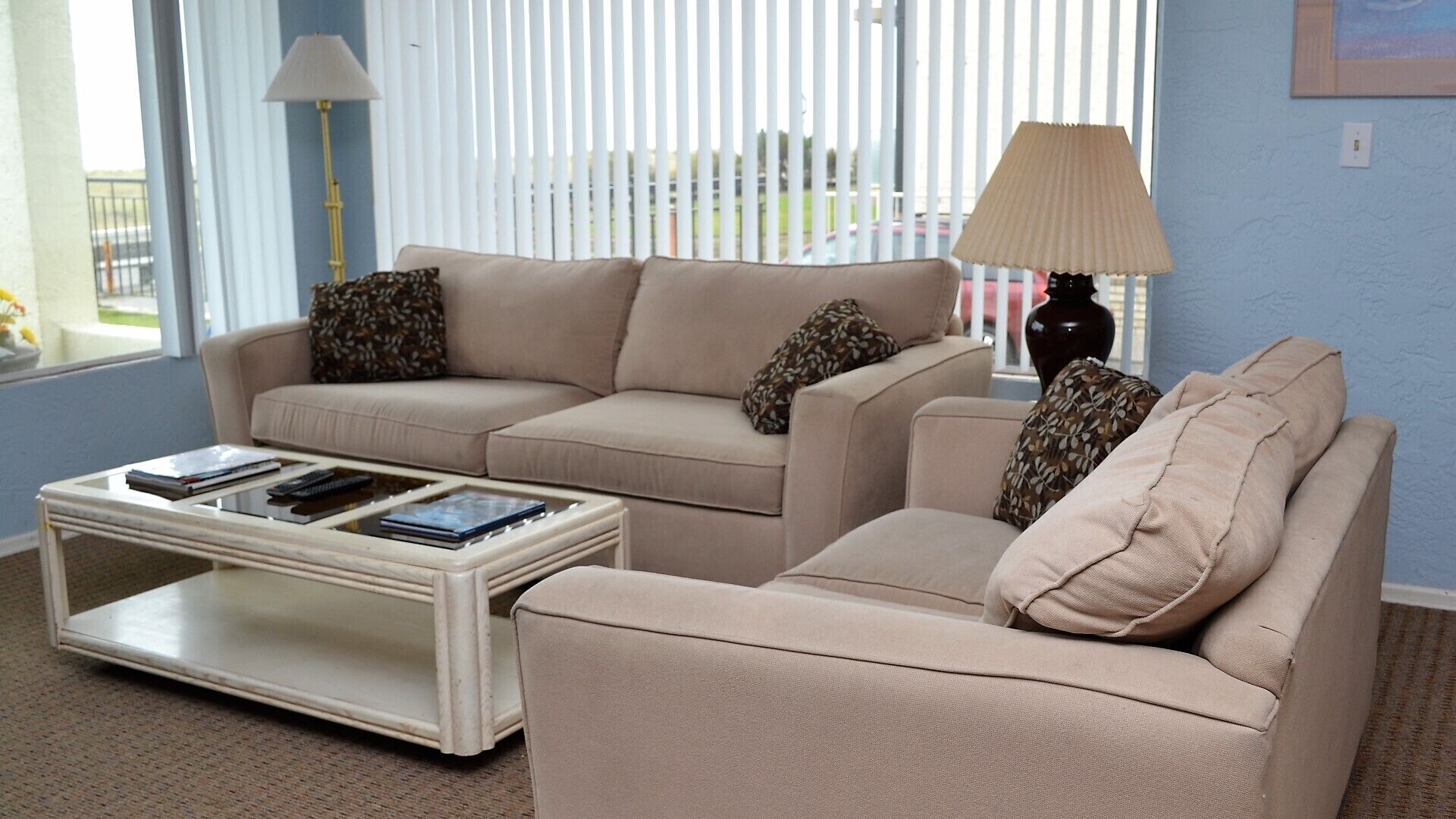 Un salon avec deux canapés beige, une table basse blanche et une lampe.