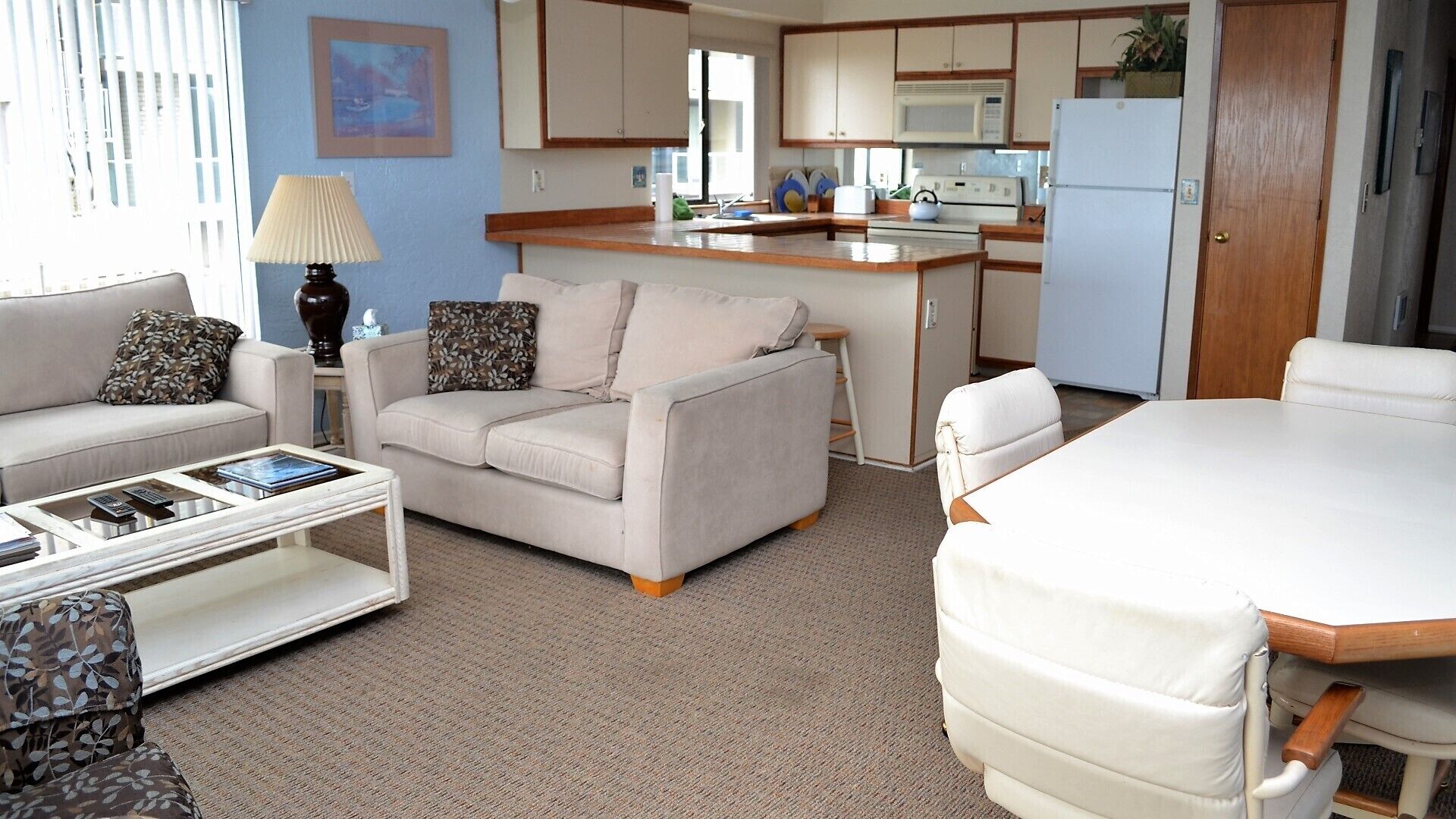 A compact living space with a sofa, a coffee table, a dining table, and a kitchen area with cabinets and appliances.
