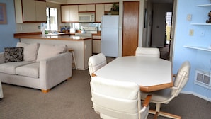 Un espacio habitable compacto con kitchenette, una mesa de comedor con sillas y un sofá.