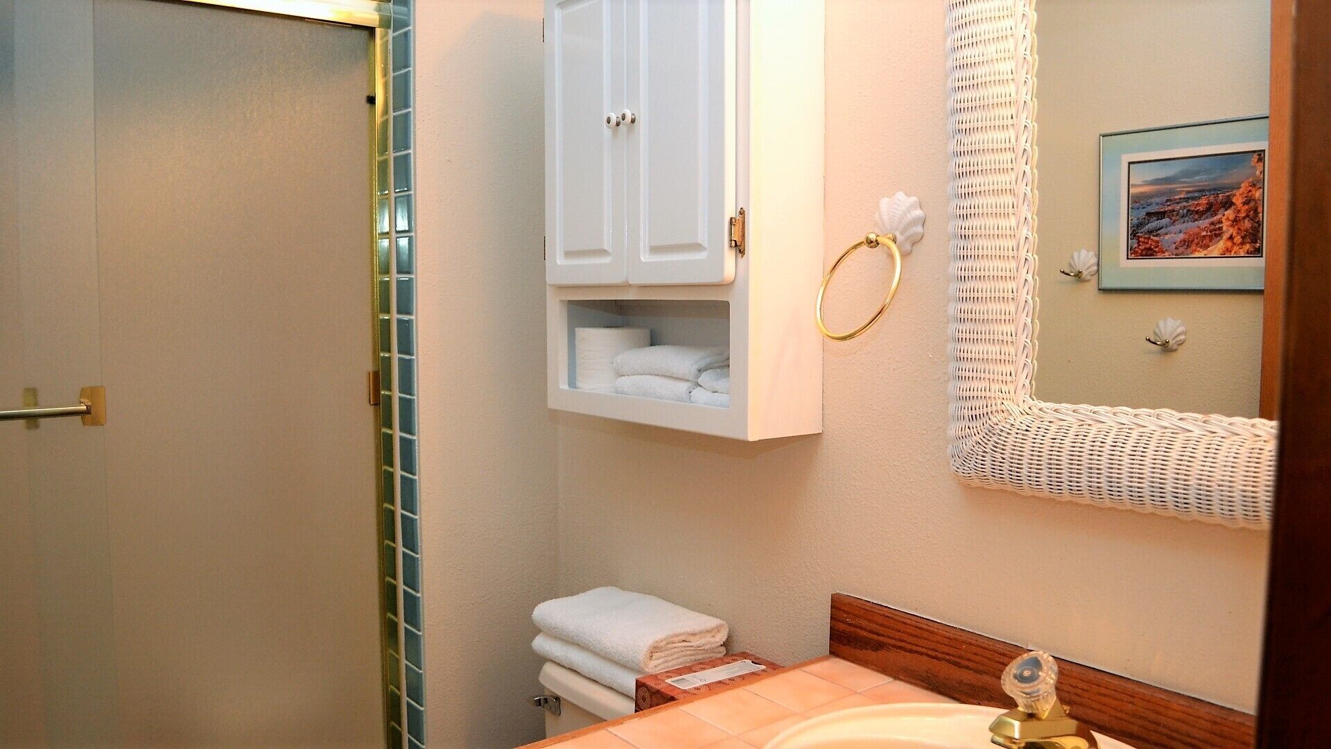 A bathroom with a shower, a toilet, a sink, and a mirror.