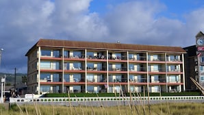 Un hotel de varios pisos con balcones, una torre del reloj y un letrero que indica un club de playa.