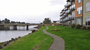 A riverside walkway leading to a multi-story building with balconies. - 2Bed/2Bath Upscale, River Front Condos. Close to Beach & Convention Ctr (Seaside)