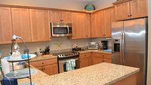 A kitchen with wooden cabinets, a stainless steel refrigerator, a microwave, a stove, and a toaster. - 2Bed/2Bath Upscale, River Front Condos. Close to Beach & Convention Ctr (Seaside)