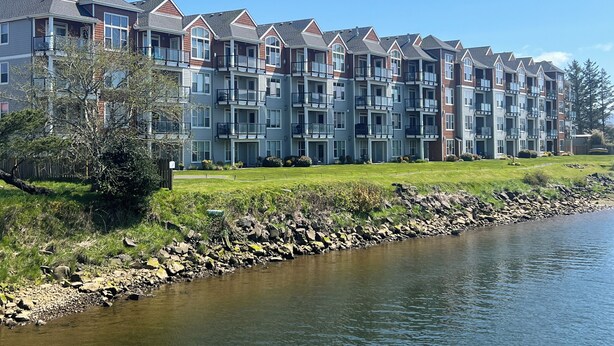 A multi-story residential building with balconies, located beside a river. - 2Bed/2Bath Upscale, River Front Condos. Close to Beach & Convention Ctr (Seaside)
