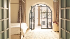 Een slaapkamer met een bed, een groot rondboogvenster en een plafondventilator.