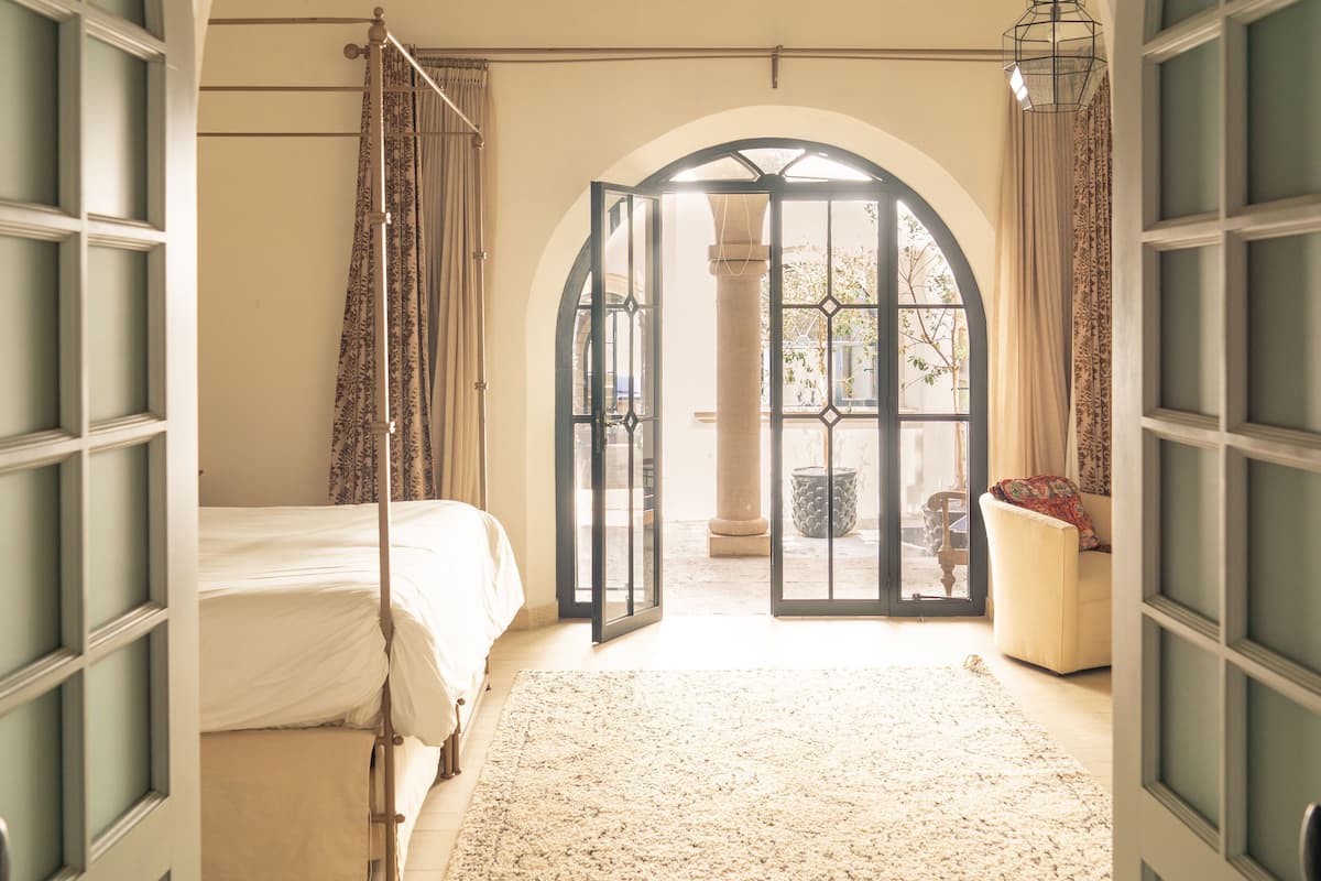 Ein Schlafzimmer mit einem Bett, einem großen Bogenfenster und einem Deckenventilator.