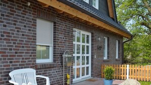 A brick house with a white door, a mailbox, and a bench outside. - Vacation apartment North Sea (OG) (Sellin)