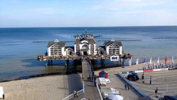 A pier with a row of white buildings, a sandy beach, and the sea in the background. - Vacation apartment North Sea (OG) (Sellin)