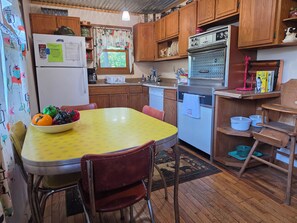 Una cocina con armarios de madera, un refrigerador, una estufa y una mesa de comedor con sillas.