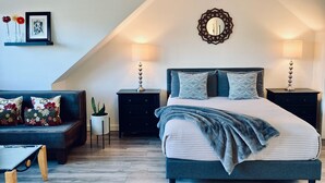 Una camera da letto con un letto, comodini, una lampada, uno specchio e un divano.