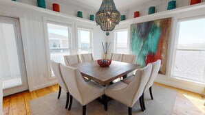 Ein Esszimmer mit einem Holztisch, weißen Stühlen, einer Dekoschüssel und einer Chandelier.