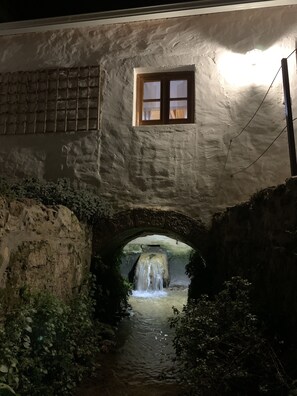 Un pont de pedra amb una petita finestra i una cascada sota.