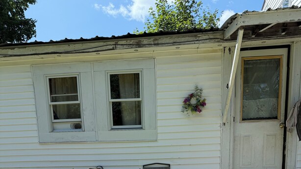 A wooden deck with a table and chairs, a white house with two windows, and a door with the number 4. - Rustic intown country apartment on the Moosehead trail (Sangerville)