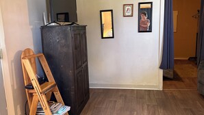 A room with a wooden floor, a dark wooden cabinet, a wooden ladder, and a mirror on the wall. - Rustic intown country apartment on the Moosehead trail (Sangerville)
