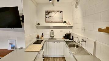 A compact kitchen with white cabinetry, a central island, a built-in stove, and a wall-mounted TV.