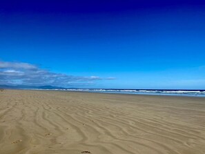 Une vaste plage de sable fin, avec de douces vagues à l'horizon.