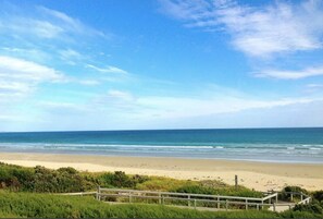 A beach with a wooden walkway leading to the shore, clear skies, and calm ocean waves. - Prom Coast 3 ~ Beach Getaway ~ Stunning Beach! (Sandy Point)