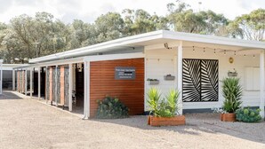 A modern building with a sign for 'Prom Coast Apartments' and a covered outdoor area with plants.